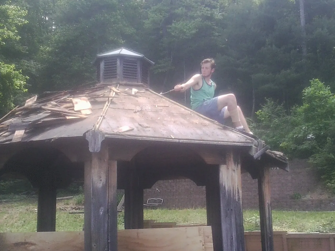 Tearing the old roof off a wooden gazebo before new shakes in Lamar